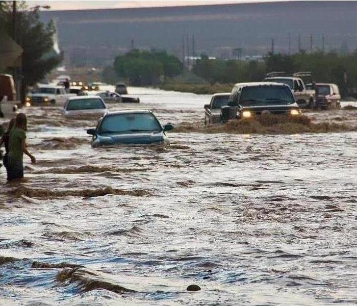 Flooding in a street with cars driving through it